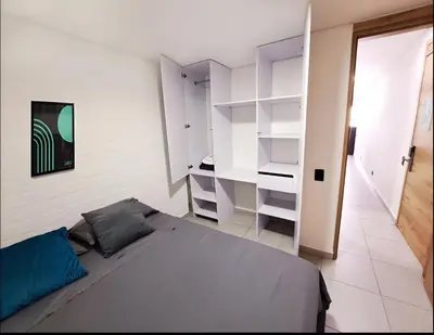 a bedroom with a bed and white shelves at INVERSO Coliving in Medellín