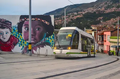 a bus driving down a street next to a mural at INVERSO Coliving in Medellín