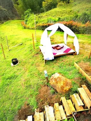 a tent in a field with a pile of wood at Hillside Cabins - Guatapé in Medellín