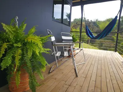 a patio with a hammock and a chair and a plant at Hillside Cabins - Guatapé in Medellín