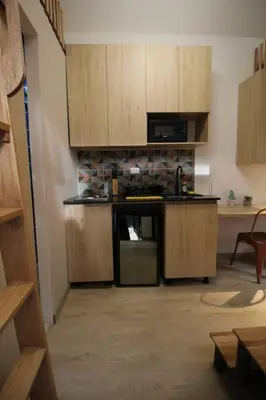 a kitchen with wooden cabinets and a black refrigerator at Nueva Tiny House en el Poblado FRN110 By Roots Rentals in Medellín