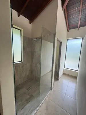 a walk in shower in a room with two windows at Casa Fuego in La Pintada