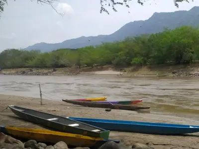 a group of boats sitting on the shore of a river at Casa Rio y Montaña Low cost in Honda