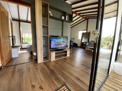 a living room with a flat screen tv and wooden floors at Casa campestre descanso relajación jacuzzi BBQ amplias zonas verdes in Carmen de Viboral