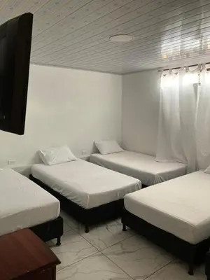a room with three beds and a tv in it at Hotel Mallorca Estadio, Medellin in Medellín
