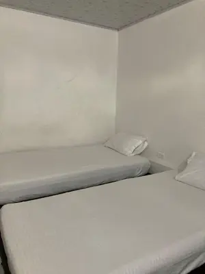 two beds in a small room with white walls at Hotel Mallorca Estadio, Medellin in Medellín