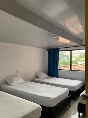 two beds in a room with a window at Hotel Mallorca Estadio, Medellin in Medellín