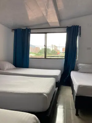 a group of three beds in a room with a window at Hotel Mallorca Estadio, Medellin in Medellín