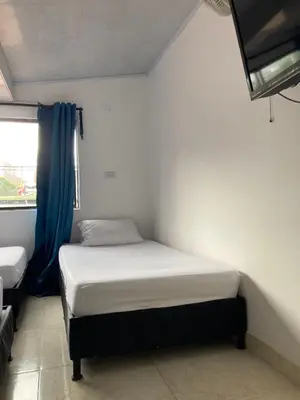 a small bedroom with a bed and a window at Hotel Mallorca Estadio, Medellin in Medellín