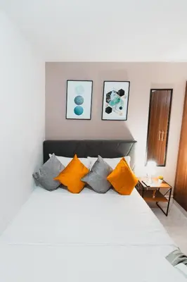 a bedroom with a white bed with orange and grey pillows at AC - House Laureles - Self Cheking in Medellín