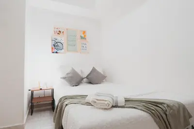 a white bedroom with a bed and a table at AC - House Laureles - Self Cheking in Medellín
