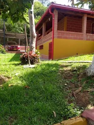 a yellow and red house with a tree in the yard at Villa Yolanda in Girardota