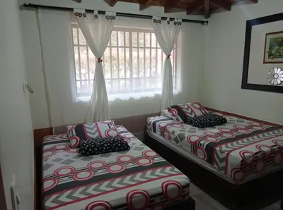 two beds sitting in a room with a window at Villa Yolanda in Girardota
