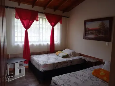 a bedroom with two beds and a window with red curtains at Villa Yolanda in Girardota