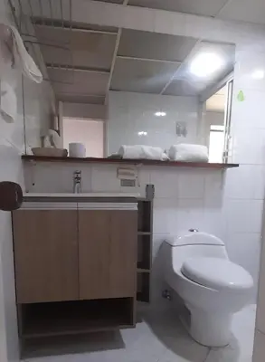 a bathroom with a toilet and a sink and a mirror at Hotel Laureles 70 Medellín in Medellín