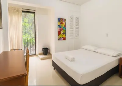a white bedroom with a bed and a window at Hotel Laureles 70 Medellín in Medellín