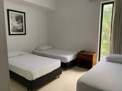 a room with three beds and a window at Hotel Laureles 70 Medellín in Medellín