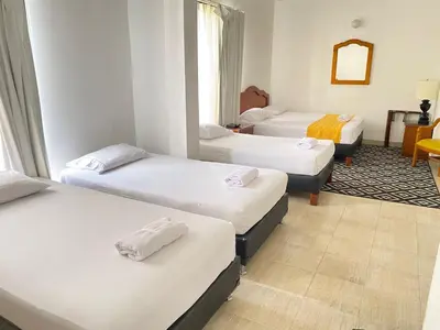 a room with three beds in a room at Hotel Laureles 70 Medellín in Medellín