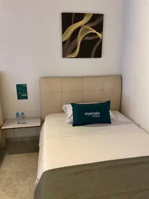 a bed with a blue pillow on top of it at Hotel boutique San Pablo H3 in Medellín