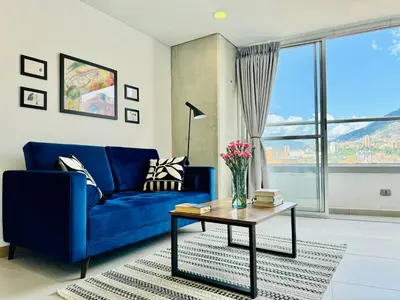 a living room with a blue couch and a table at Loft luminoso y moderno con excelentes vistas in Medellín