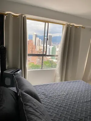 a bedroom with a bed and a large window at En la cima y en el corazón de Medellín in Medellín