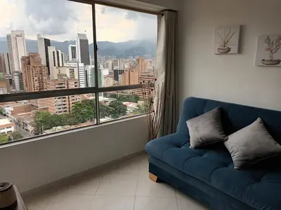 a blue couch in a room with a large window at En la cima y en el corazón de Medellín in Medellín