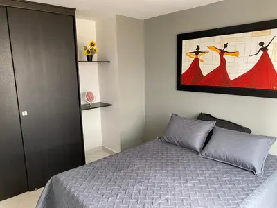 a bedroom with a bed and a painting on the wall at En la cima y en el corazón de Medellín in Medellín