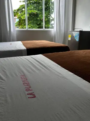 two beds in a room with a white comforter at LA PLAZOLETA in Doradal