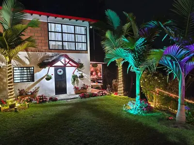 a house with palm trees in the yard at night at Desconéctate! Casa de campo con vista sensacional !!! in Rionegro