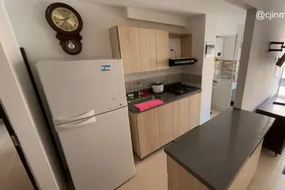 a kitchen with a refrigerator and a clock on the wall at Apartamento campestre a 5 min del parque in La Ceja