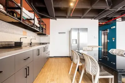 a kitchen with white cabinets and a table and chairs at Económicas habitaciones amobladas en Medellín con oficinas, puesto de trabajo, cocina, baño y lavandería comunes Be Together by Roots Rentals TOG401y402 in Medellín