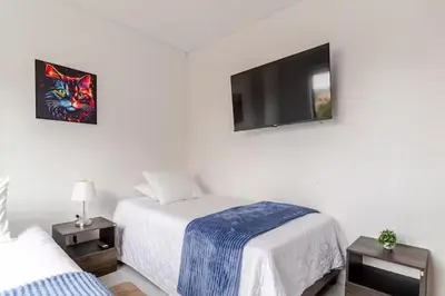 a bedroom with two beds and a flat screen tv at Apartamento centro Marinilla in Marinilla