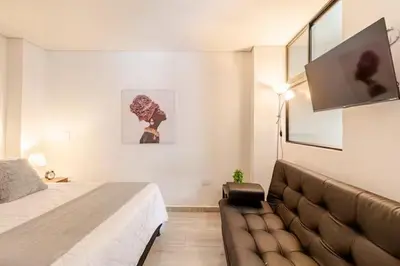 a bedroom with a couch and a flat screen tv at Apartamento centro Marinilla in Marinilla