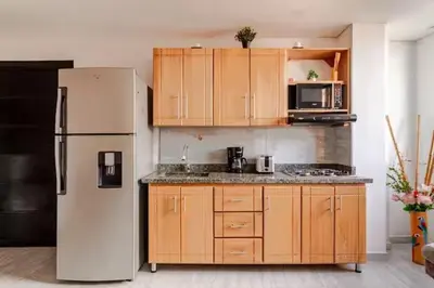 a kitchen with a white refrigerator and wooden cabinets at Apartamento centro Marinilla in Marinilla