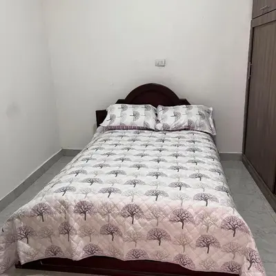 a bed with a pink comforter and pillows on it at Casa Familiar- Turística Manríque Medellín in Medellín