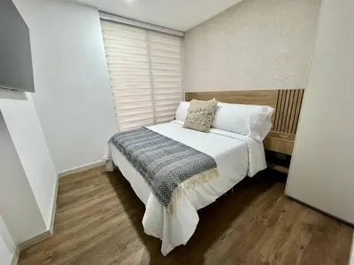 a bedroom with a large bed with white sheets and pillows at Great view apartment in El Poblado in Medellín