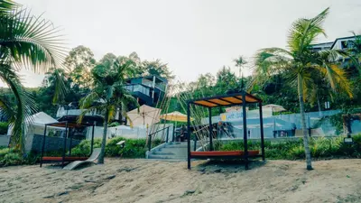 a playground on a beach with palm trees and a building at Viajero Guatapé Hostel & Lake Club in Guatapé