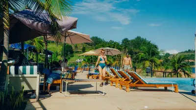 a woman in a bikini is walking by a pool at Viajero Guatapé Hostel & Lake Club in Guatapé