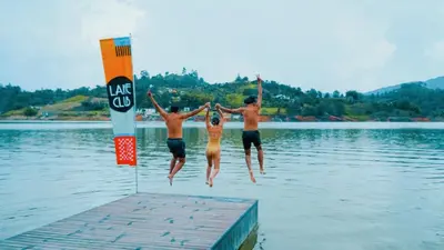 three people jumping off a dock into a lake at Viajero Guatapé Hostel & Lake Club in Guatapé