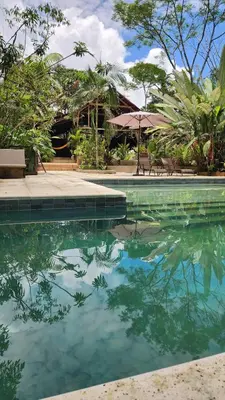 a pool of water with chairs and an umbrella at Casa Kiwi Jungle Lodge in San Francisco