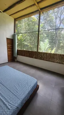 a bedroom with a bed and a large window at Casa Kiwi Jungle Lodge in San Francisco