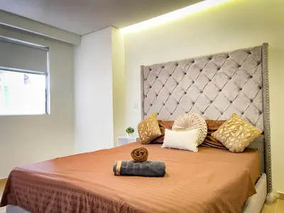 a bedroom with a large bed with a large headboard at Apt luxe laurles estadio 3alcobas in Medellín