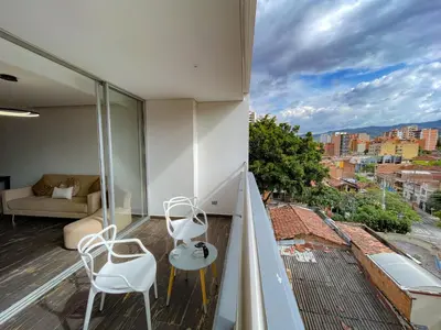 a balcony with two white chairs and a couch at Apt luxe laurles estadio 3alcobas in Medellín