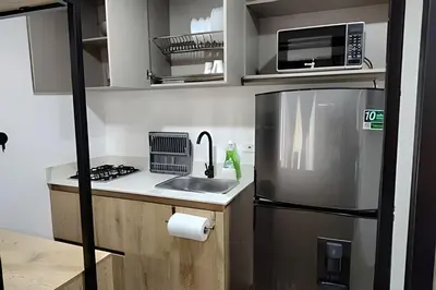 a small kitchen with a refrigerator and a microwave at Acogedor Loft en la floresta cerca al metro in Medellín