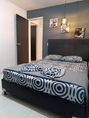 a bedroom with a bed with a black and white comforter at E2P RENOVADO y BELLO APARTAMENTO EN LAURELES ESTADiO in Medellín