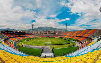 an empty stadium with yellow seats and a green field at E2P RENOVADO y BELLO APARTAMENTO EN LAURELES ESTADiO in Medellín