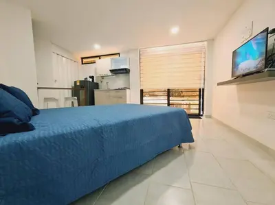 a bedroom with a blue bed and a kitchen at Comfy loft in Laureles in Medellín