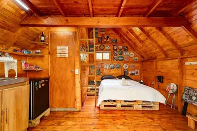 a bedroom with a bed in a wooden cabin at Cabaña en la Naturaleza con Jacuzzi - Santa Elena in Medellín