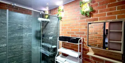 a bathroom with a glass shower and a brick wall at 1BR Air Conditioned Studio Buenos Aires in Medellín