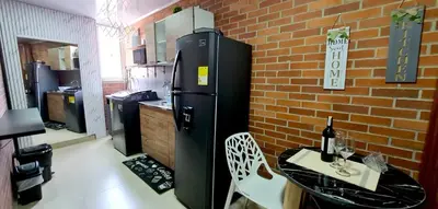a kitchen with a black refrigerator and a table and a brick wall at 1BR Air Conditioned Studio Buenos Aires in Medellín